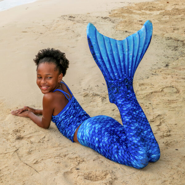 Meisje met blauwe zeemeerminstaart op het strand